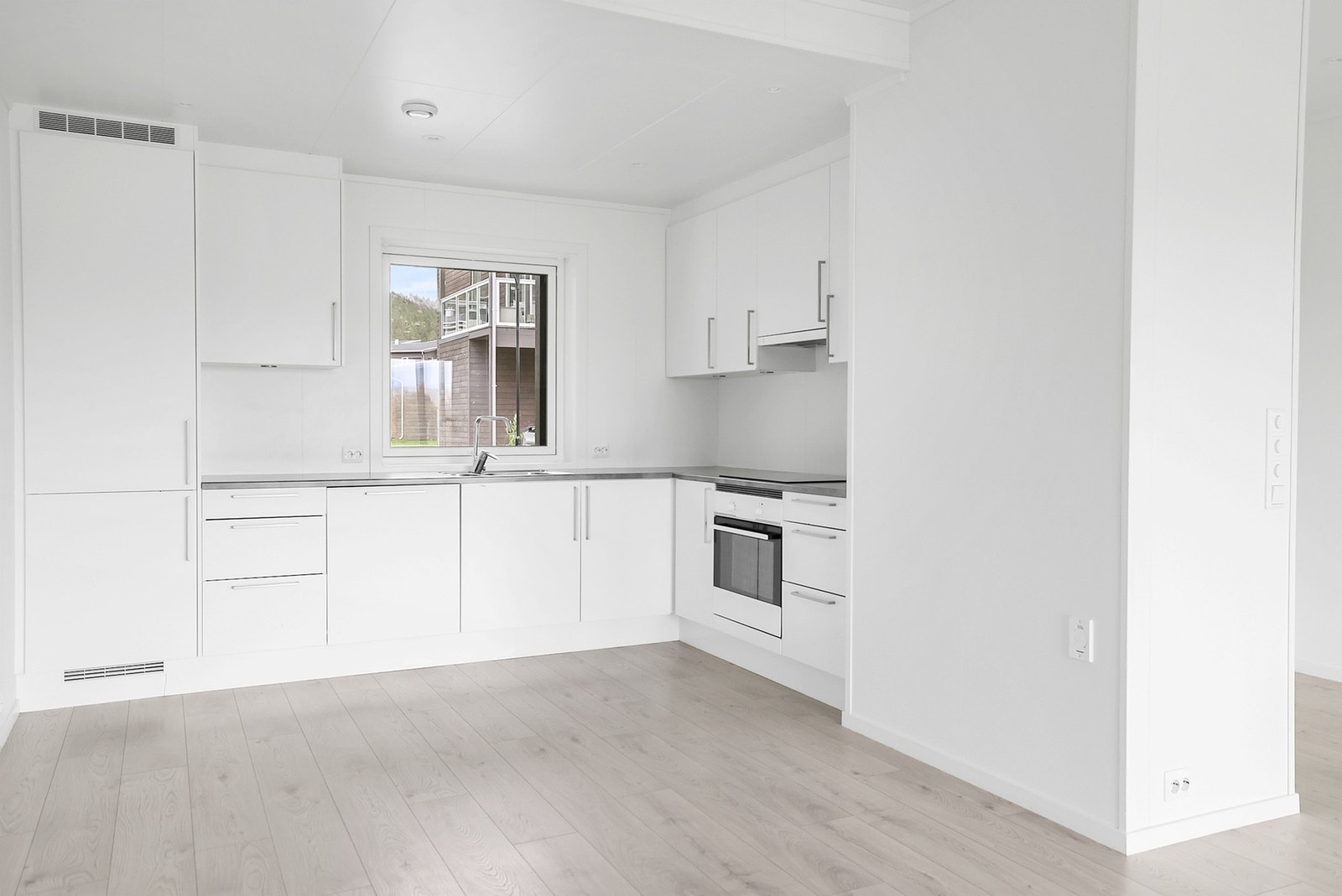 Kjøkkenet har en lys, slett innredning fra Sigdal og benkeplate av laminat. Galleribilde