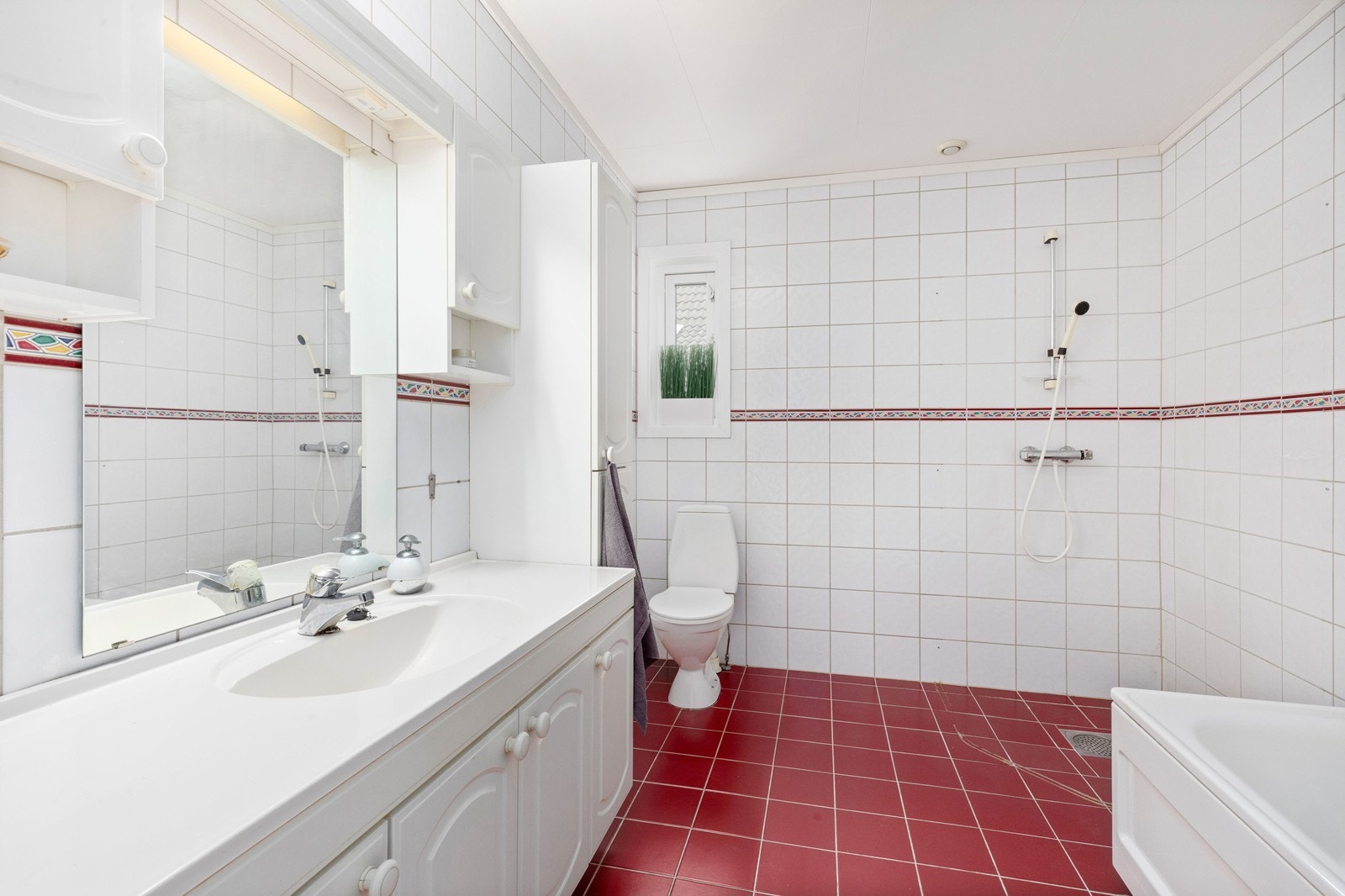 Romslig flislagt bad med wc, dusjhjørne, badekar og servant Galleribilde