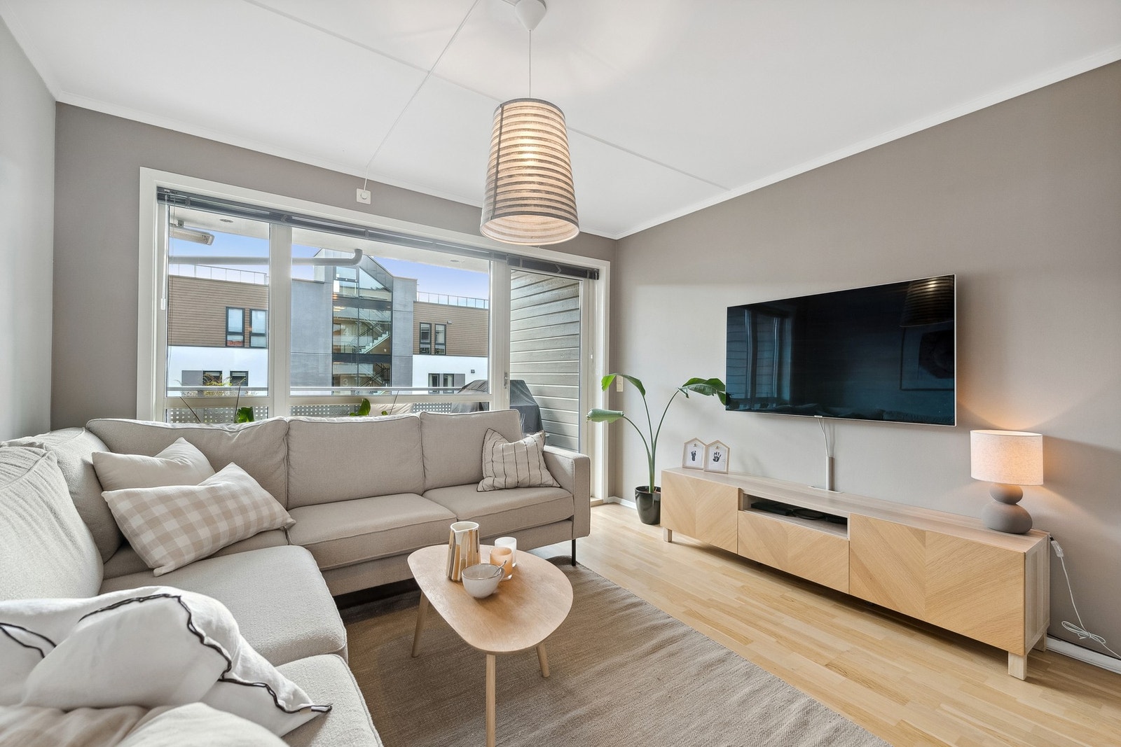 Lys og pen stue med parkett på gulv og en gjennomgående planløsning med balkong på begge sider Galleribilde