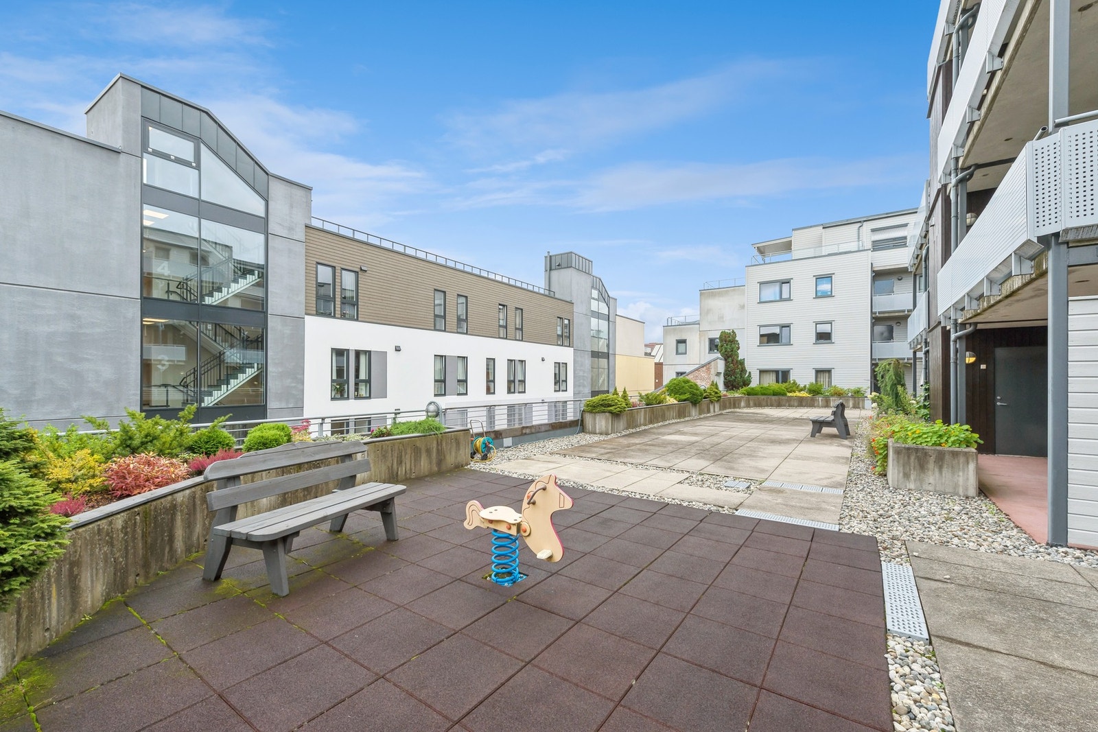 Pent opparbeidede fellesområder med lekeplass, sittegrupper og beplantning Galleribilde