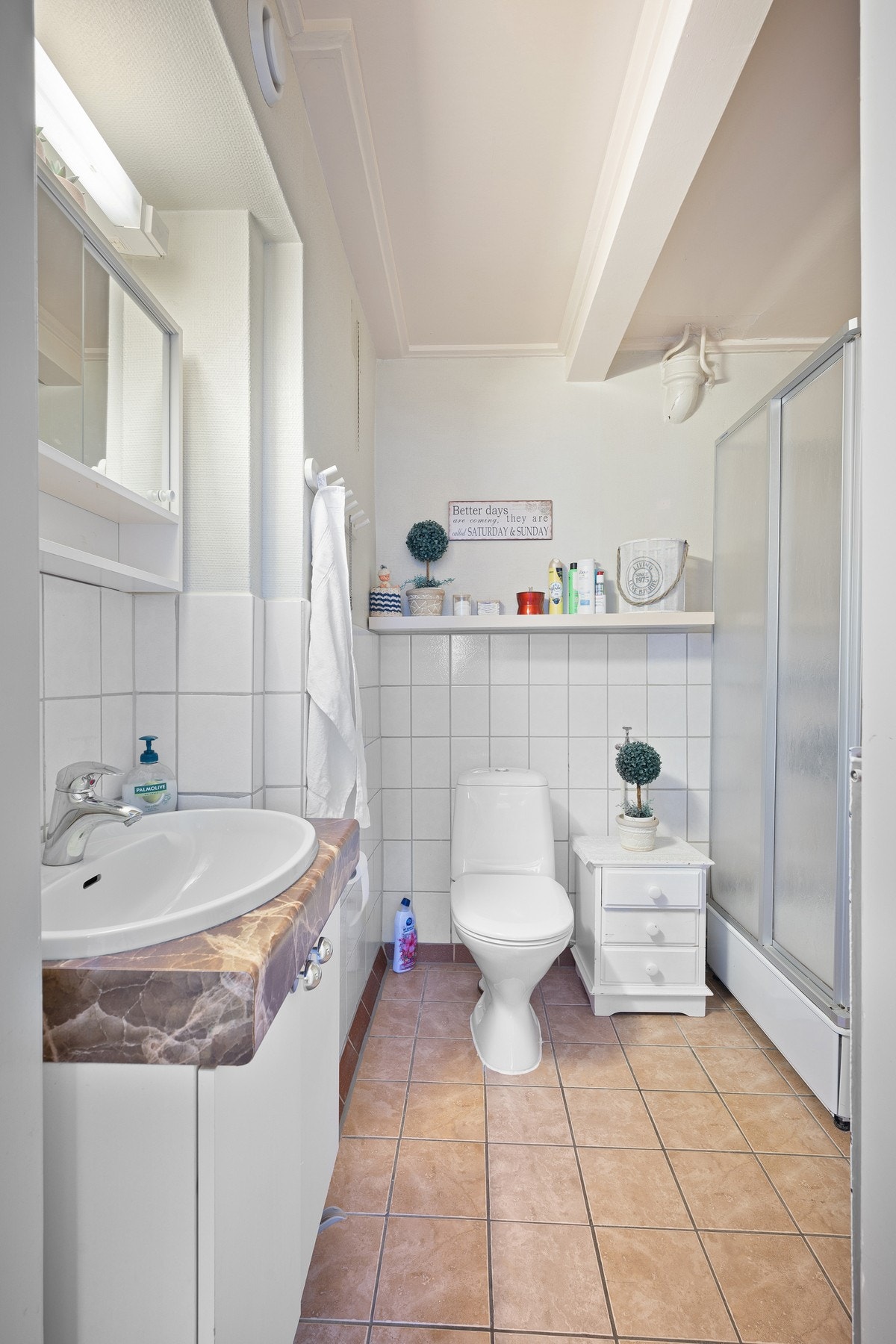 Badet har flislagt gulv, delvis flislagte vegger og inneholder servantinnredning, toalett og dusjkabinett Galleribilde