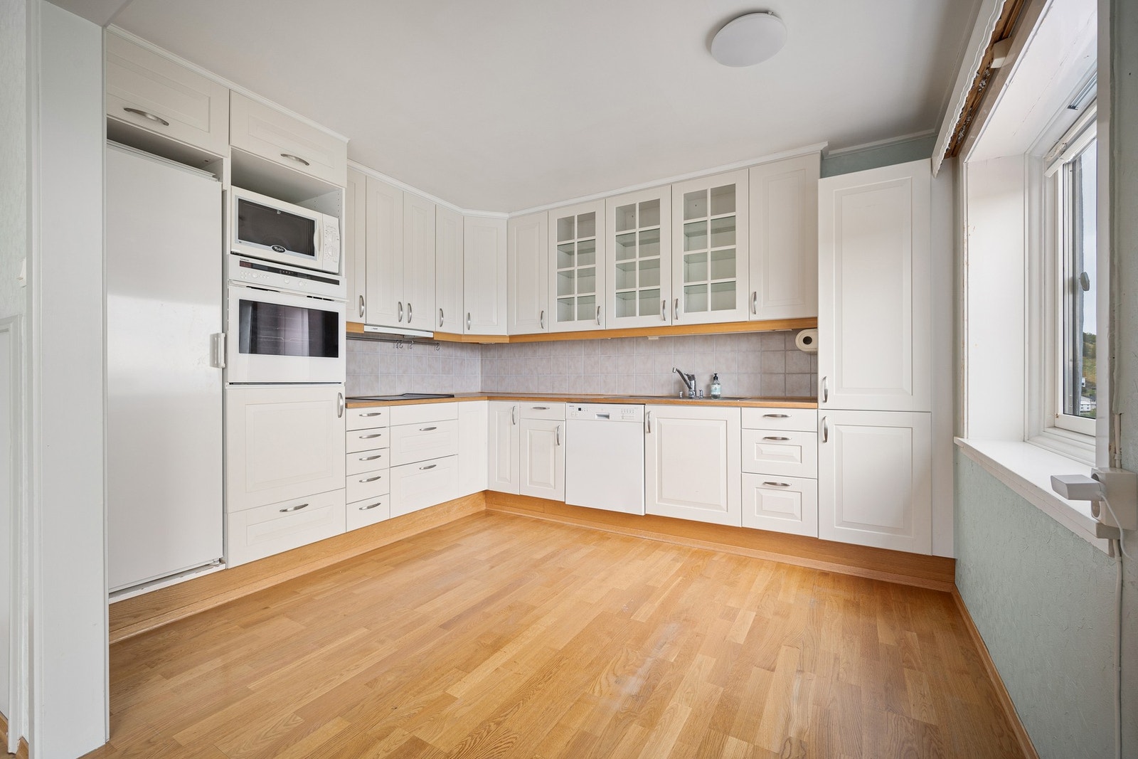 Kjøkkenet har en tidløs innredning i lyse toner, mye plass i skap/skuffer og benkeplate som gir god arbeidsplass Galleribilde