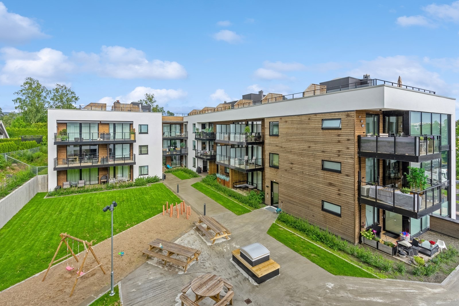 Sameiets tomt er opparbeidet med gressplen, lekeapparater og sittebenker. Galleribilde