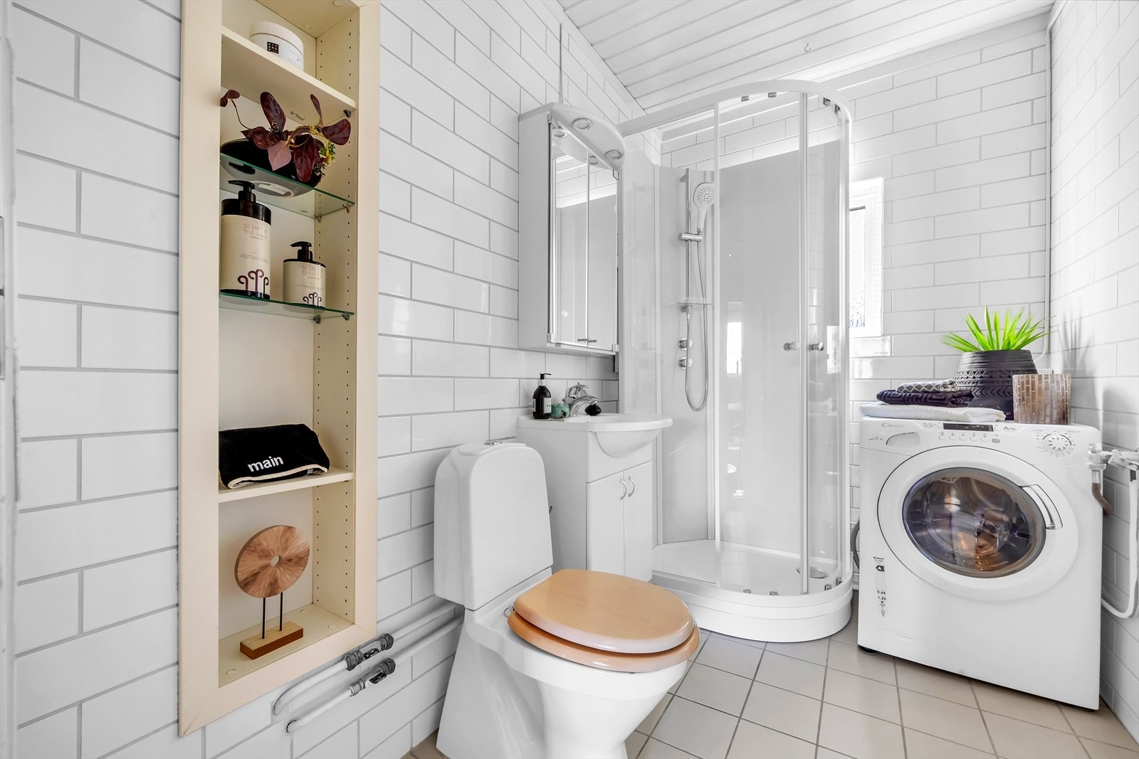 Lyst flislagt baderom med dusjkabinett (2023), opplegg for vaskemaskin, toalett og servant med oppbevaring Galleribilde