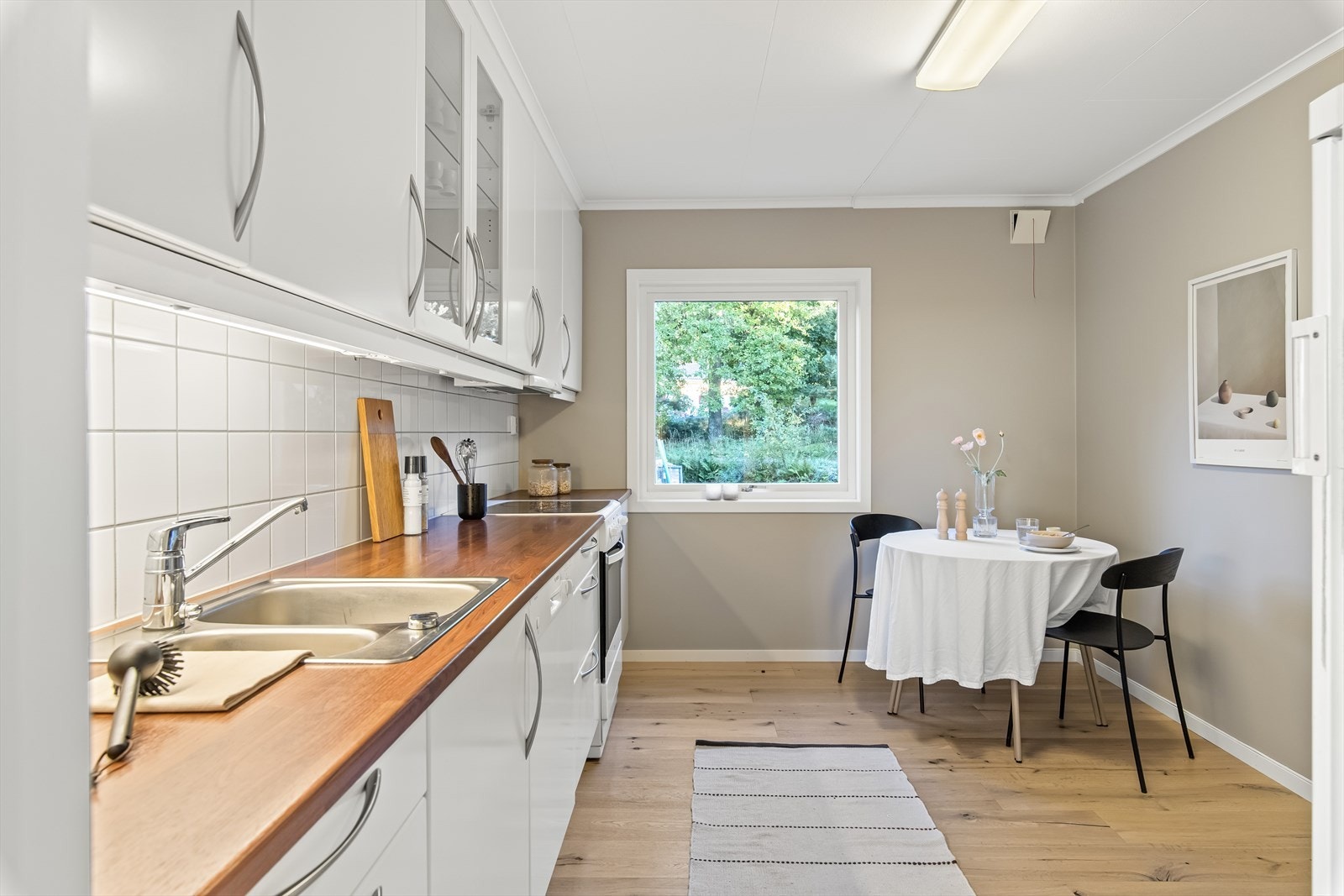 Takhøye overskap gir pen estetikk og enklere renhold. Det er integrerte hvitevarer som platetopp, stekeovn, oppvaskmaskin, samt kjøl- og fryseskap. Galleribilde