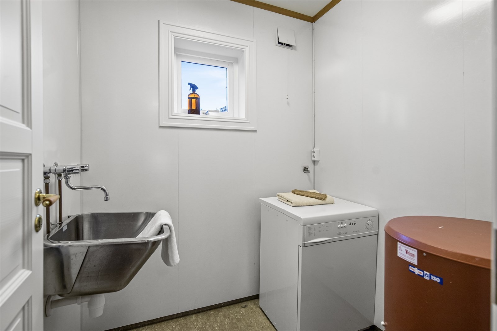 Vaskerommet ligger vegg-i-vegg med baderommet og er innredet med overflater av vinylbelegg på gulv og malte slett plater på vegger. Det er opplegg for vaskemaskin og strømuttak for tørketrommel. Galleribilde