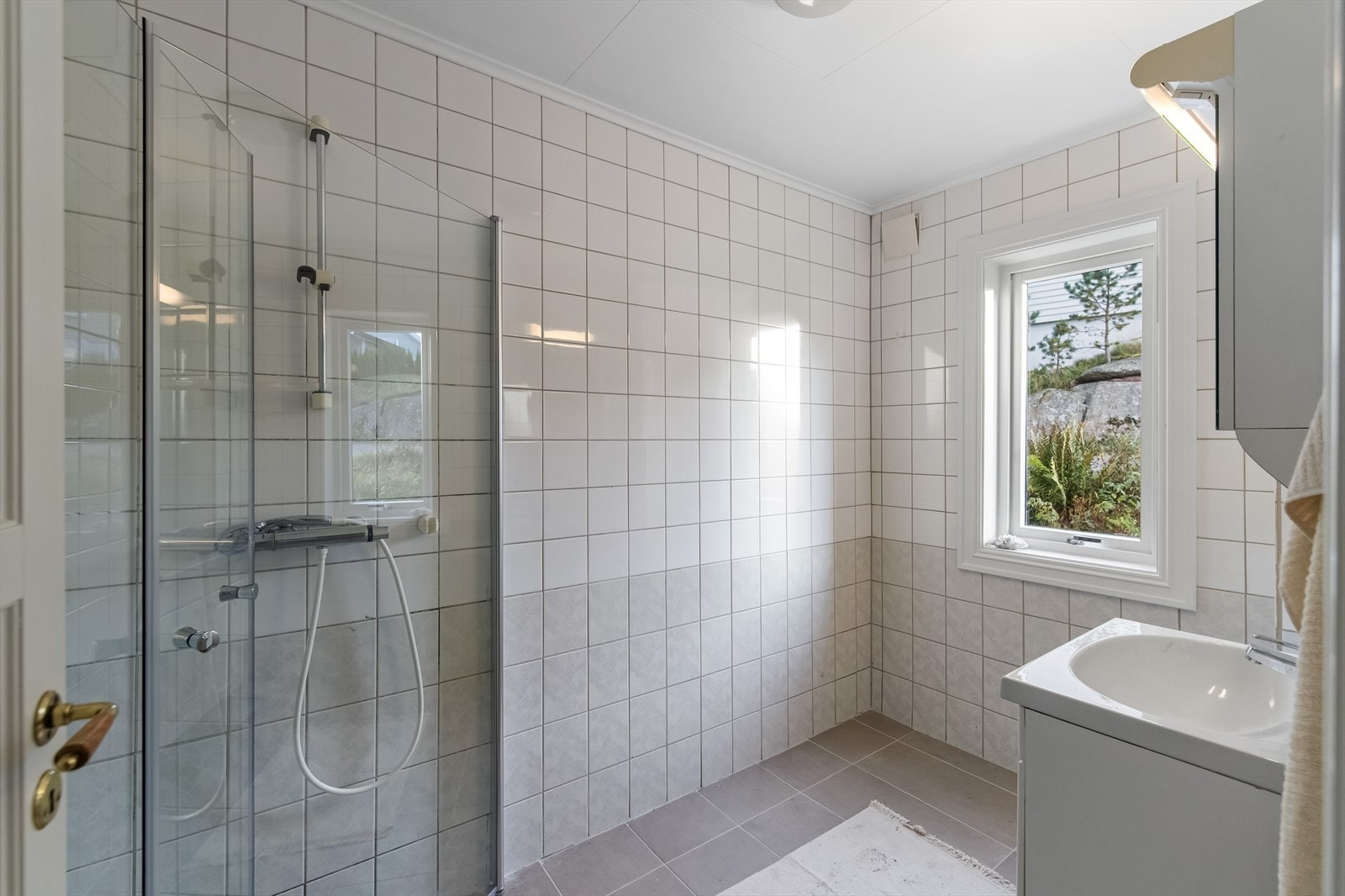 Helfliselagt baderom med dusjnisje og servantinnredning Galleribilde