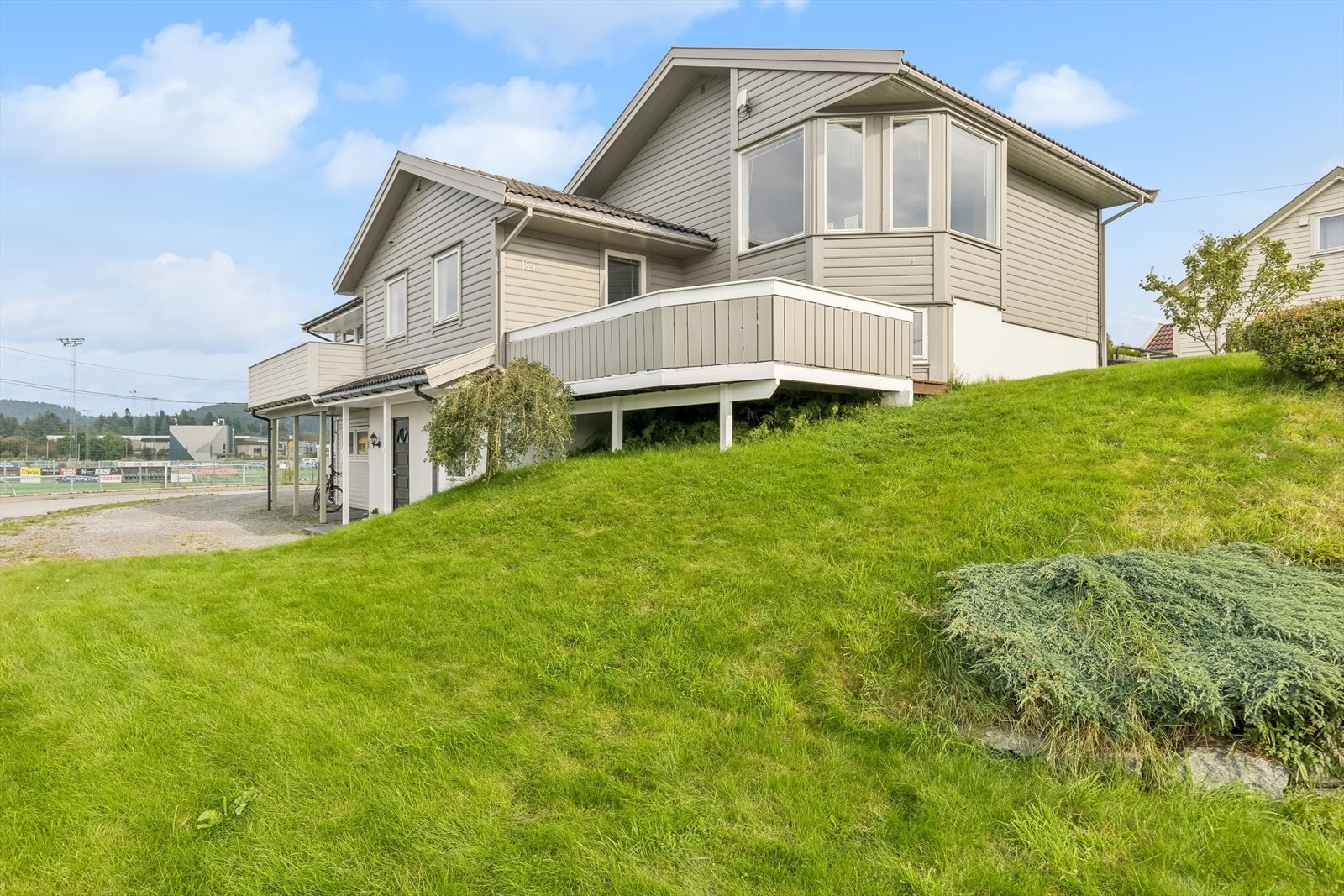 Eiendommen har gruset gårdsplass og stor plen med diverse busker og trær. Galleribilde