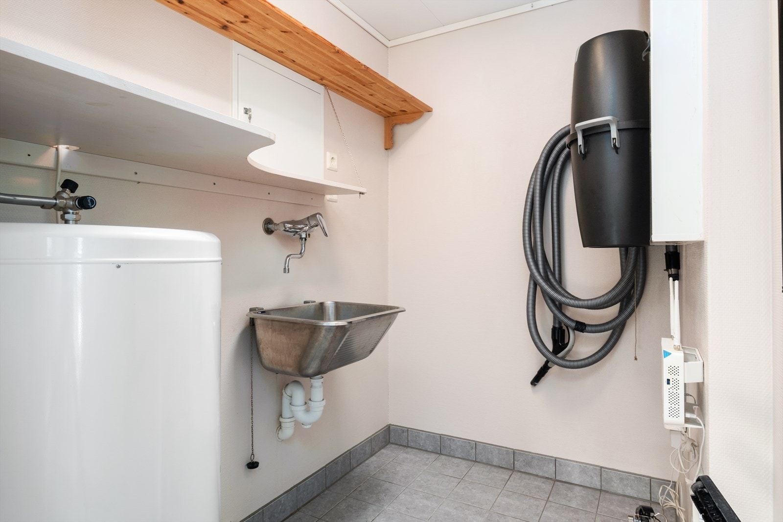 Vaskerom/Teknisk-rom er utstyrt med utslagsvask i stål, sentralstøvsugar, varmtvasstank og hyller. Galleribilde