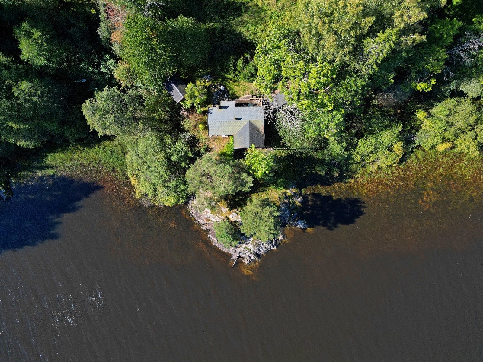 Hytta er trukket noen høydemetre opp fra vannet, og i front er det skrånende fjell. Galleribilde