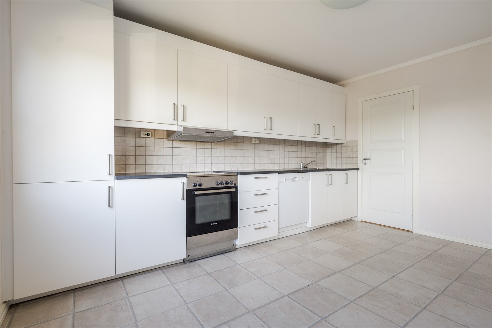 Romslig kjøkken med original innredning med slette fronter og oppvaskbenk i rustfritt stål. Over komfyren er det kjøkkenventilator med kullfilter. Galleribilde