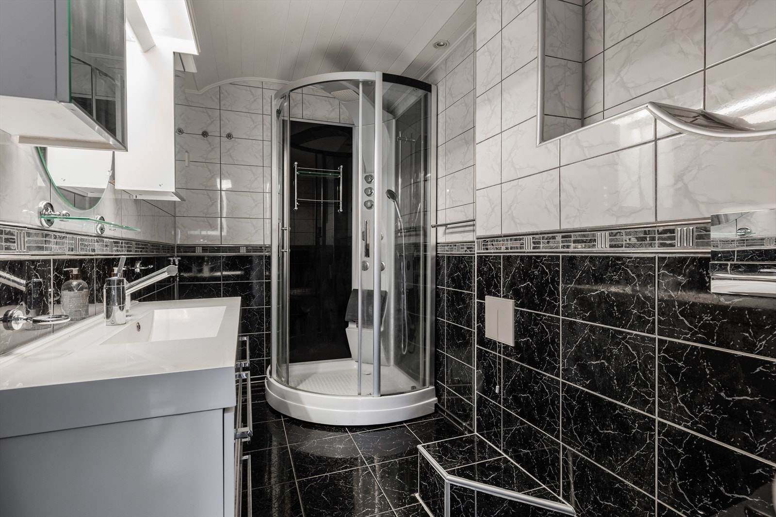 Lys baderomsinnredning med slette fronter og heldekkende servant, speil med overlys og speilskap. Galleribilde