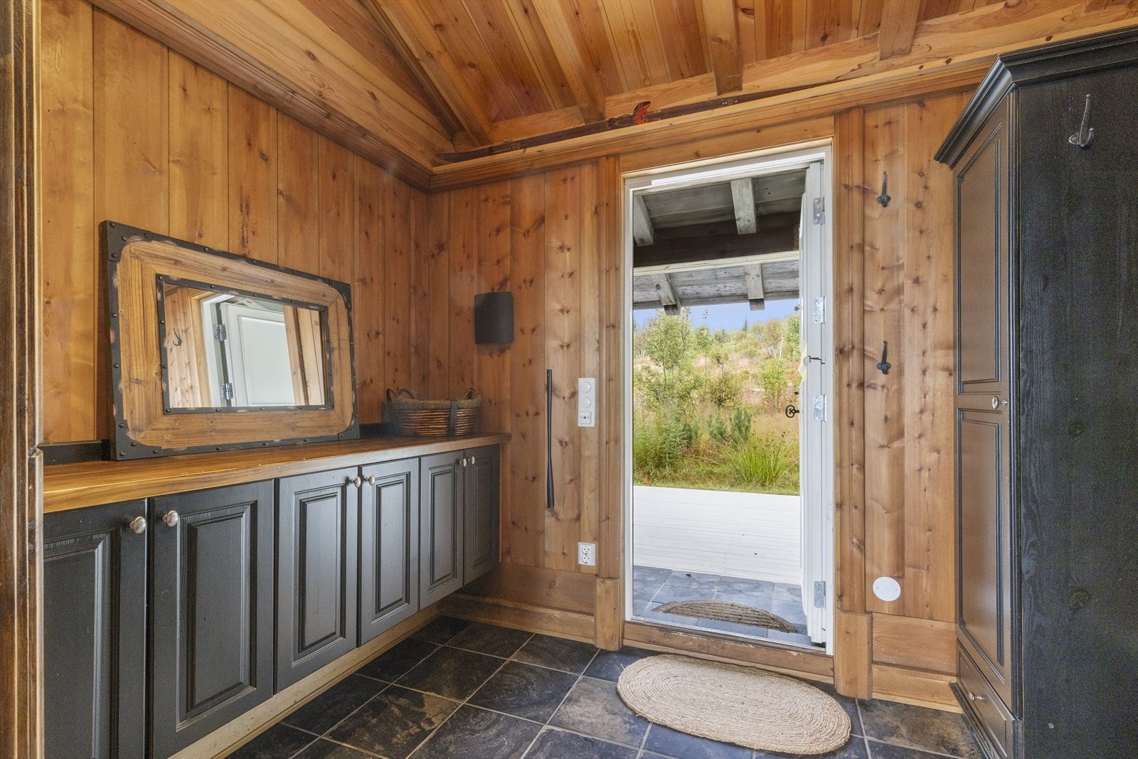 Inngangen ønsker deg velkommen inn til entreen som har veggmontert benkeskap, 2 garderoveskap med sittebenk i midten. Det er flis på gulv med termostatstyrt varme, trepanel på vegg og i himling, med spotskinne. Galleribilde