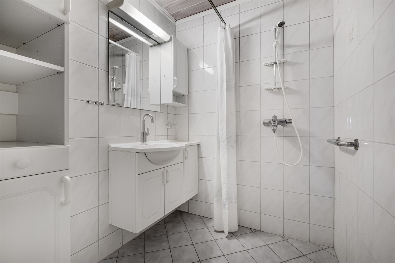 Flislagt baderom med innredning, vask og dusj. Galleribilde