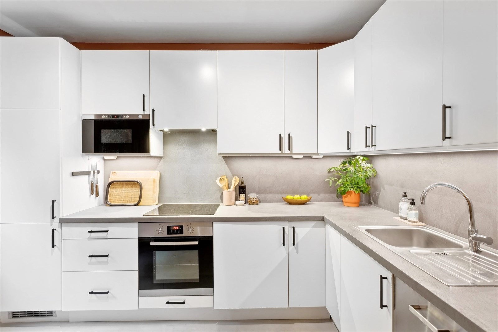 Separat og lekkert Ikea kjøkken med slette lakkerte fronter og laminat benkeplate belagt med mikrosement Galleribilde