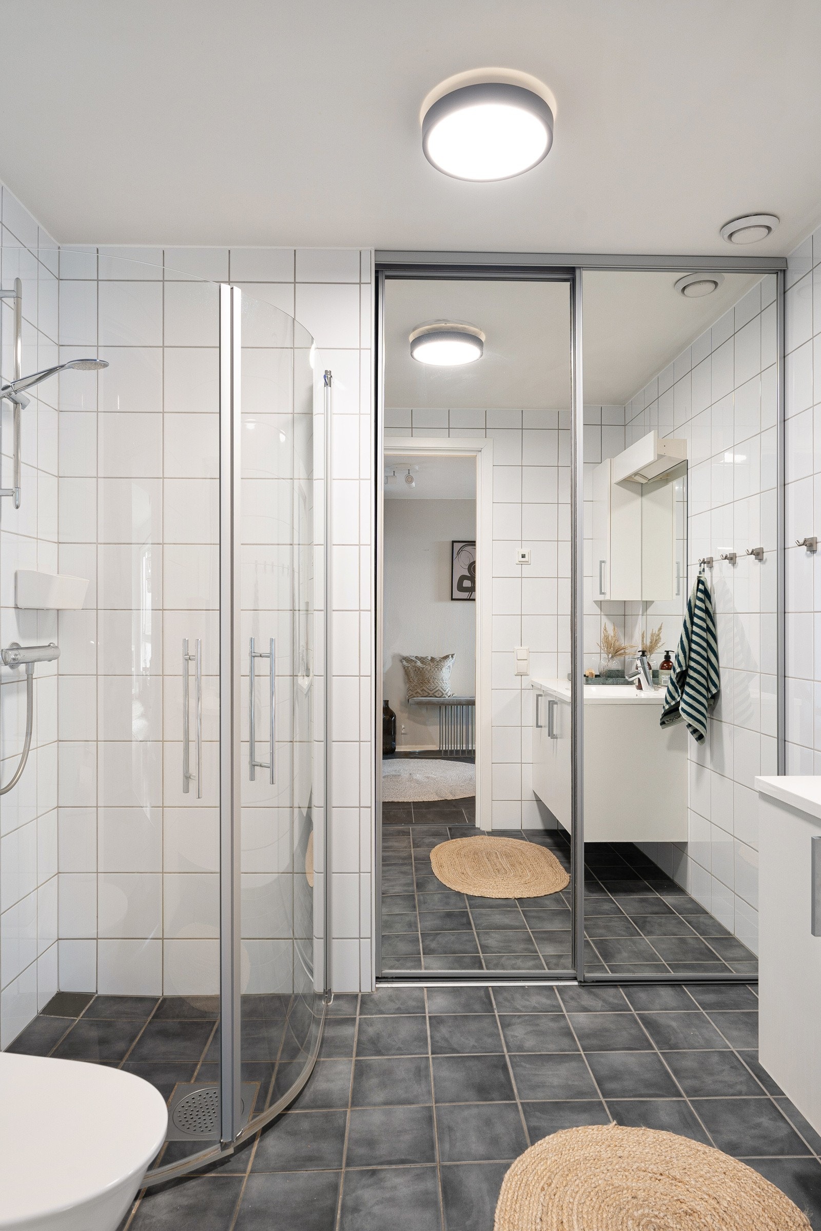 Pent og praktisk flislagt bad med stort dusjhjørne, wc og garderobeskap med plass for vaskemaskin og tørketrommel. Galleribilde