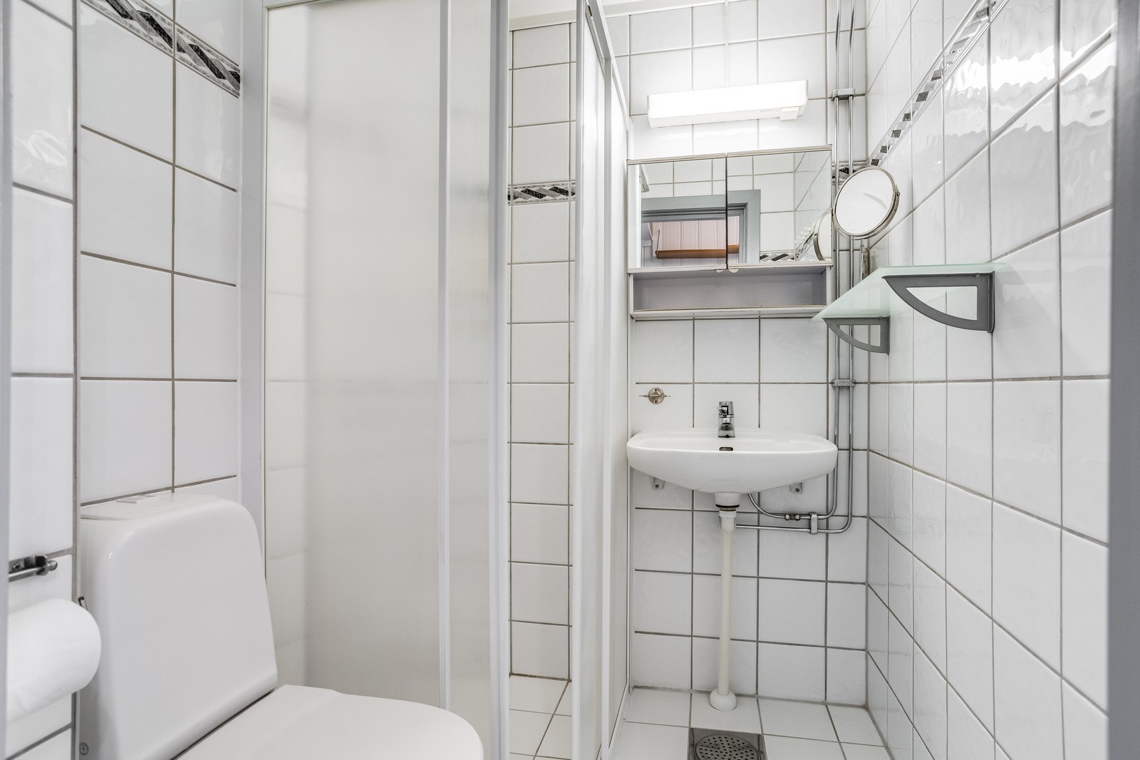 Flislagt bad med dusj, servant og toalett. Galleribilde