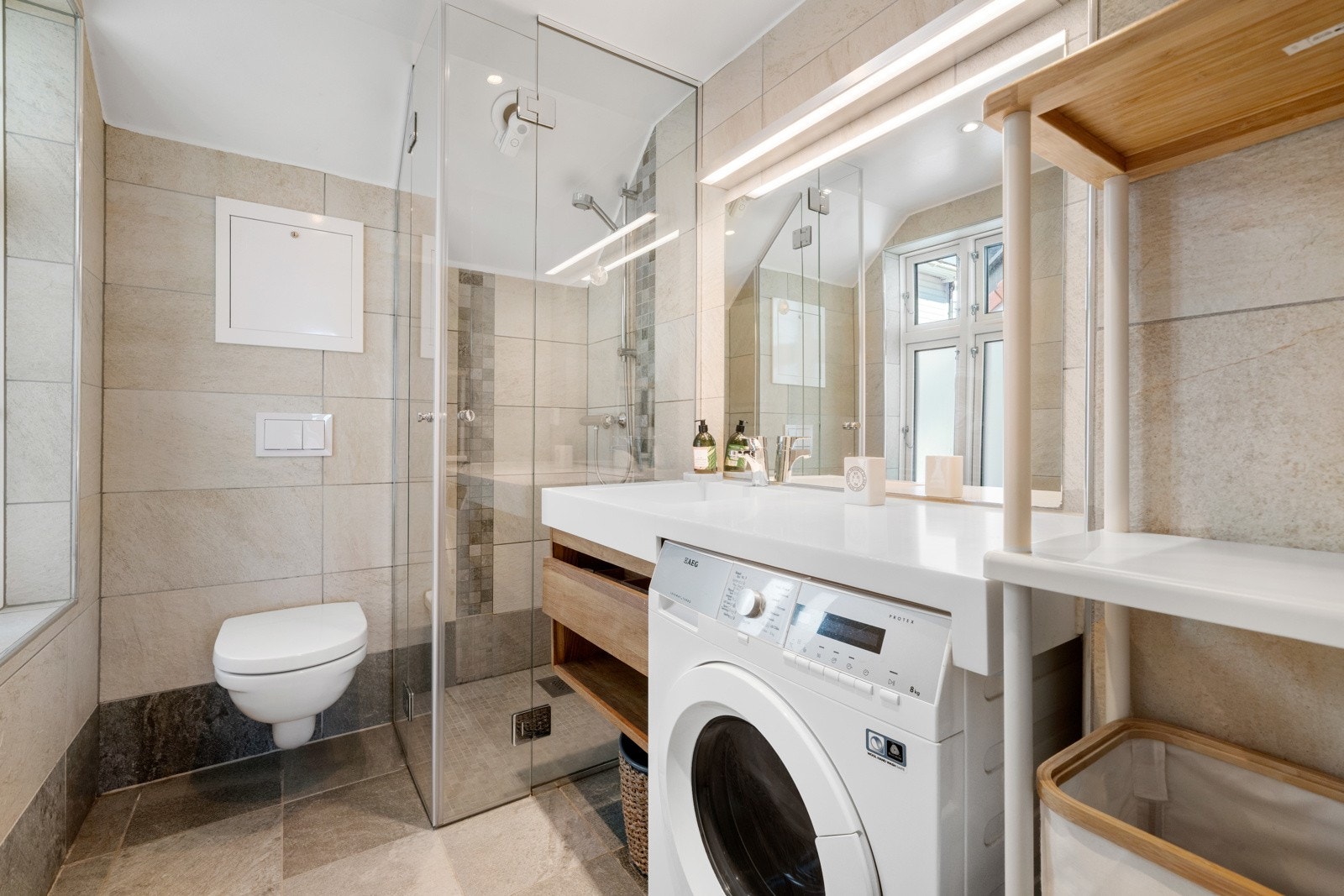 Badet er helfliset og tidløst. Opplegg for vaskemaskin, varmekabler i gulv og downlights i himling. Galleribilde