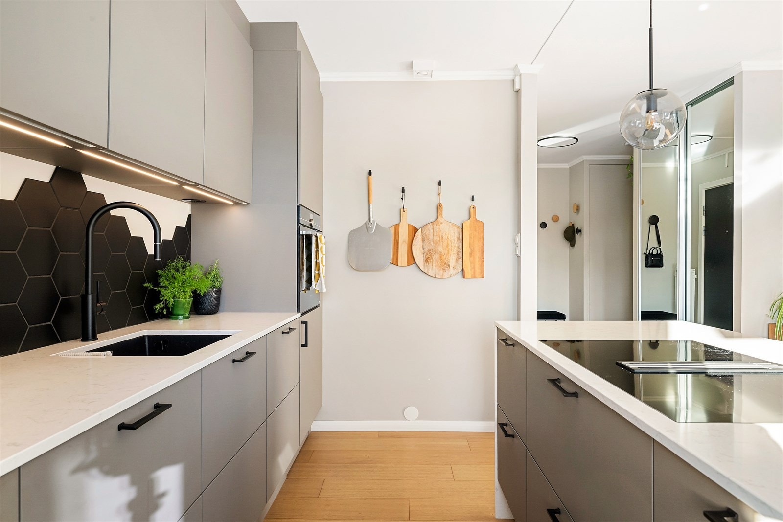 Svane kjøkkeninnredning med matte fronter og kjøkkenøy. Integrerte hvitevarer. Benkeplate fra Nerostein (Lagoon Silestone) Galleribilde