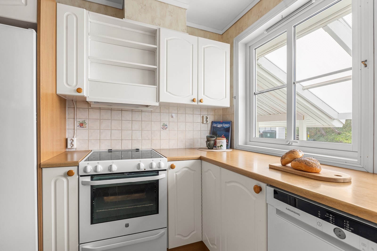 Kjøkkenet har profilerte fronter med flis over kjøkkenbenk Galleribilde