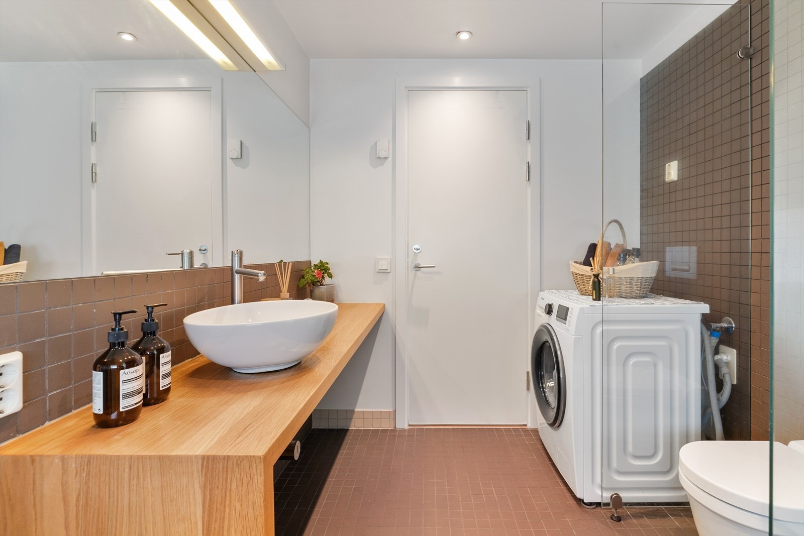 Delikat, flislagt bad med benkeplate i heltre og innfliset speil Galleribilde