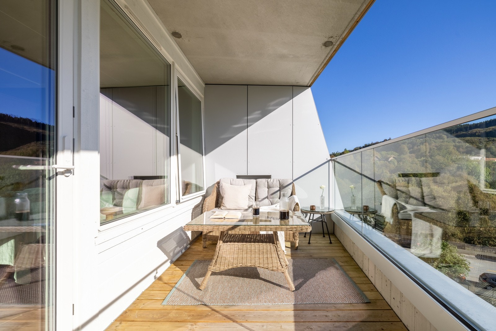 Balkongen er bekledd med terrassebord og har rekkverk av glass og stål. Galleribilde