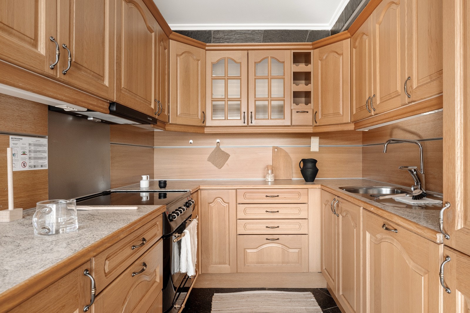 Kjøkkeninnredningen består av profilerte eikefronter og glasskap i kombinasjon med benkeplate i laminat med underlimt vask av stål. Galleribilde