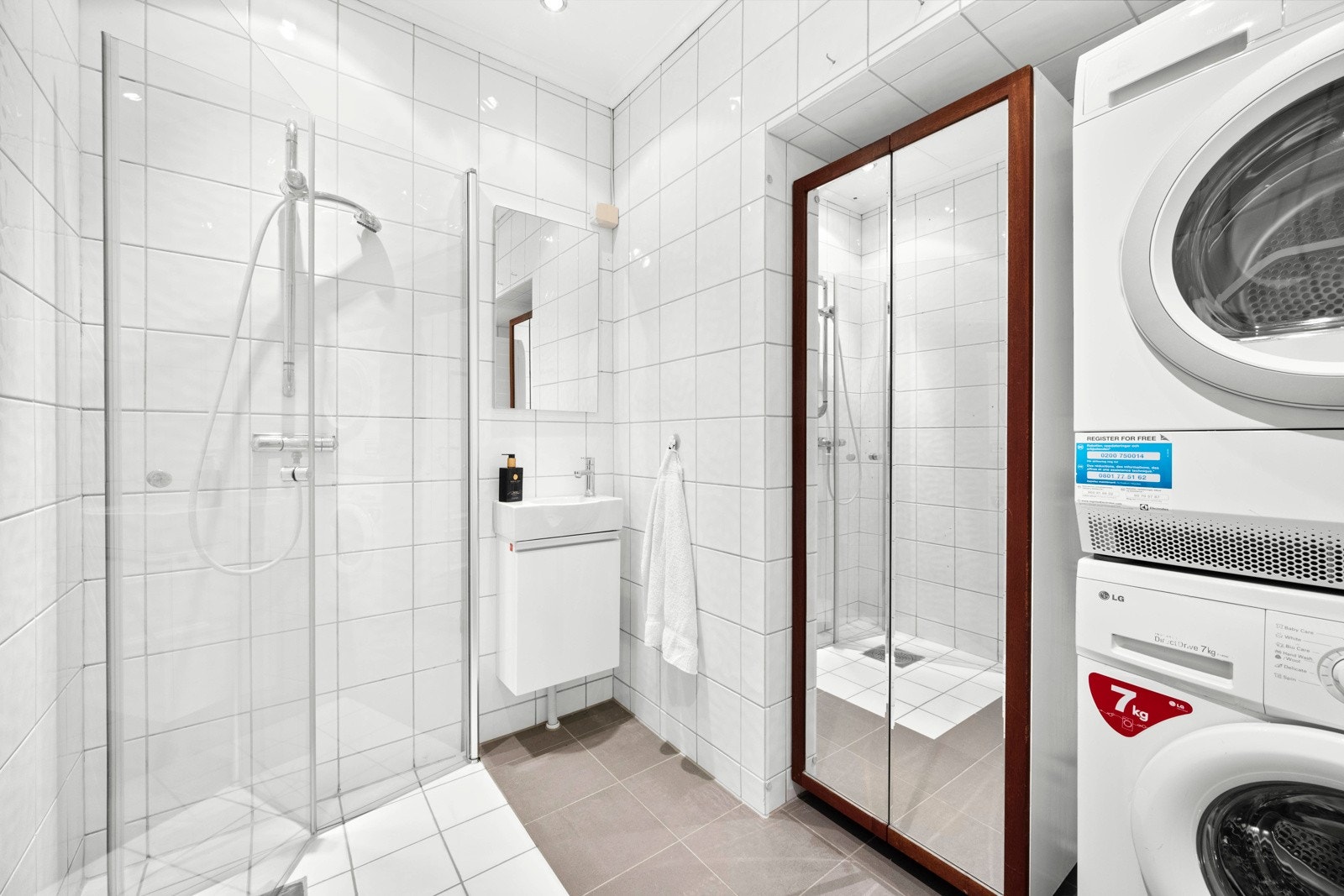 Badet har dusjhjørne med innfellbare glassdører, samt opplegg for vaskemaskin og tørketrommel. Det er også plass til et stort skap ved siden av vaskesøylen - perfekt for ekstra håndklær, vaskemiddel o.l. Galleribilde