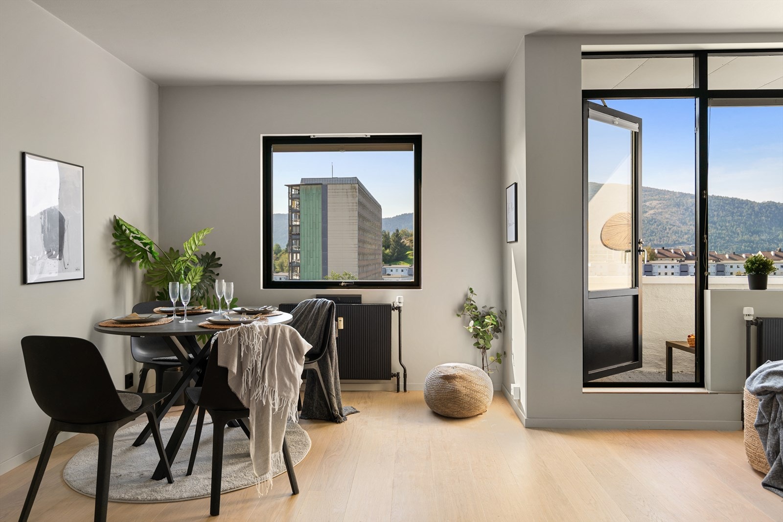 Moderne og lys stue med spiseplass, store vinduer og tilgang til balkong Galleribilde