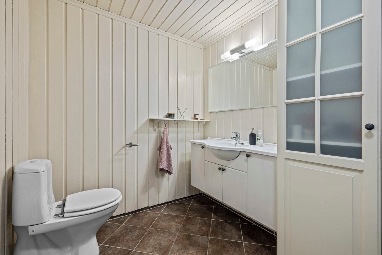 Lyst bad med fliser på gulv, og panel på vegger Galleribilde