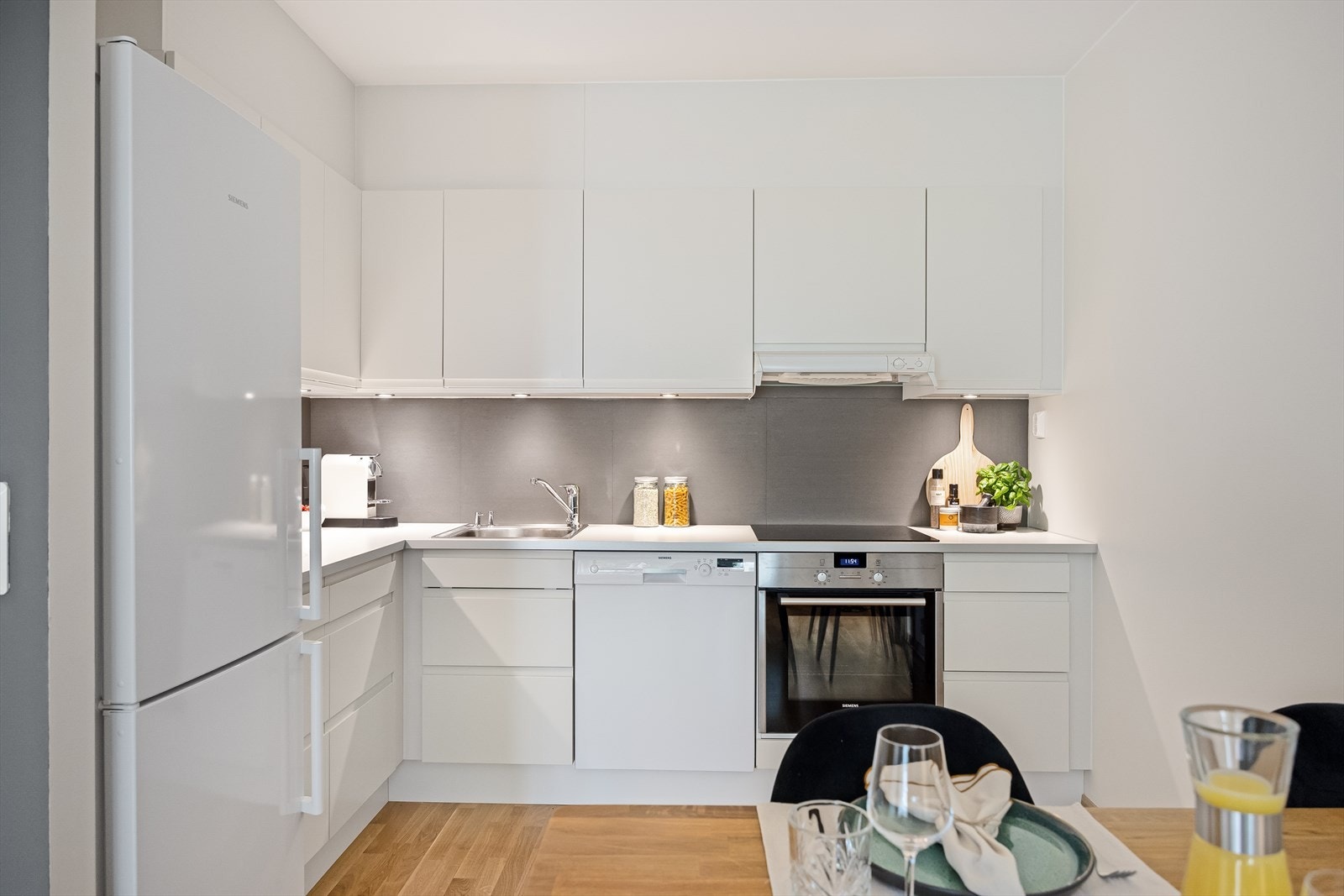 Kjøkkenet har hvite, glatte fronter, laminatbenkeplate og nedfelt oppvaskkum i rustfritt stål med ettgreps, svingbart blandebatteri. Innredningen består av både over- og underskap med lys under overskapene. Galleribilde