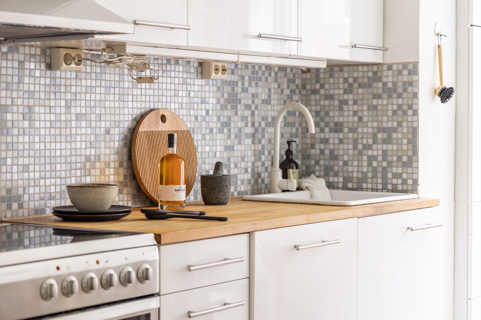 Kjøkkeninnredning fra IKEA som har laminerte fronter, heltre benkeplate, kullfilter og opplegg for vaskemaskin Galleribilde