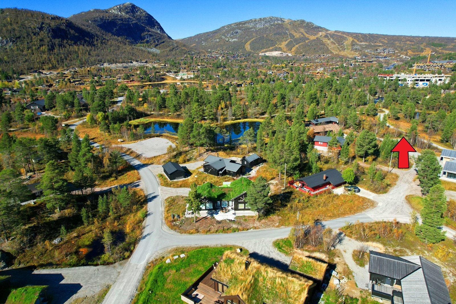 Skisenteret i bakkant. Koselig med det lille tjernet og skiløypa i bakkant. Rød pil. Galleribilde