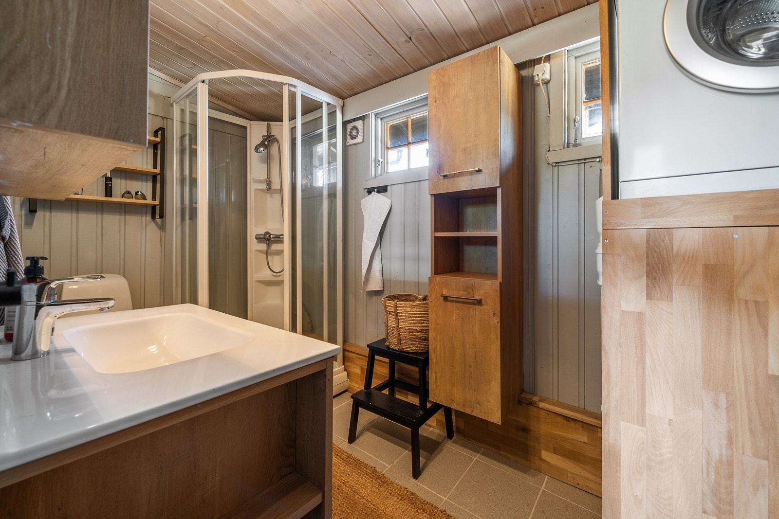 Badet med dusjkabinett, servant med skap, wc og opplegg vaskemaskin. Galleribilde