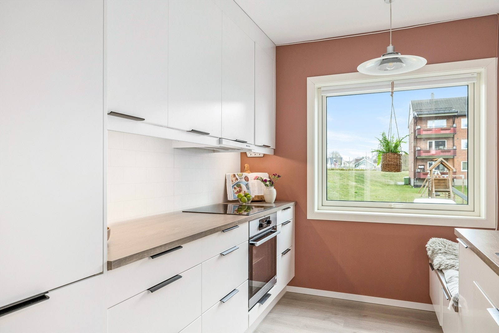 Kjøkkeninnredning har hvite slette fronter og laminert benkeplate Galleribilde