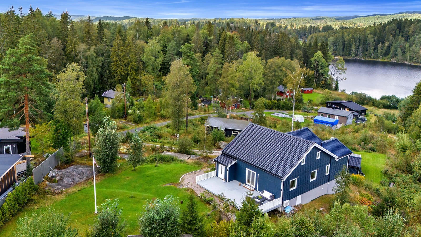 Tomten er pent opparbeidet med gressplen, prydbusker og gruslagt gårdsplass. Galleribilde