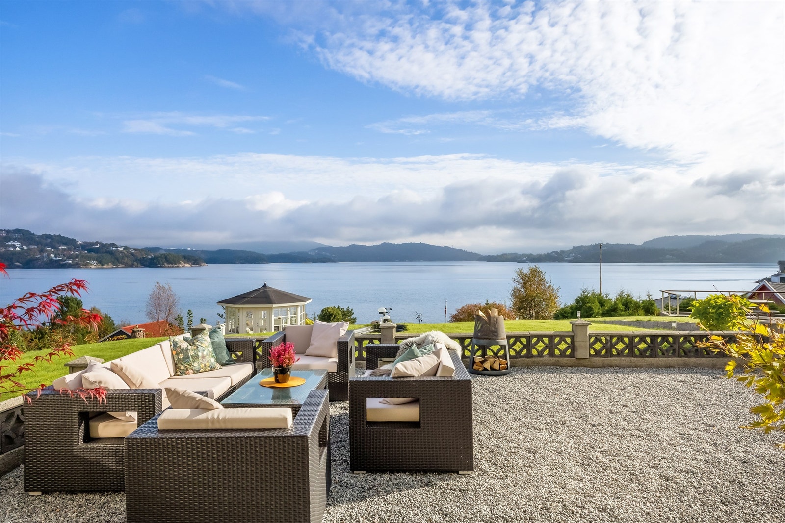 Eiendommen har flere soner for flotte uteplasser, her fra gruset plass like utenfor huset, videre ned i hage mot lysthus Galleribilde