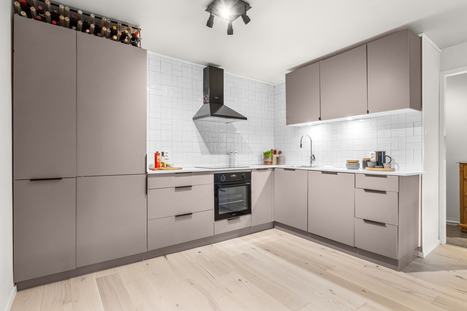 Kvik kjøkkeninnredning fra 2023 gir et moderne preg, og de glatte, folierte frontene er lette å holde rene. Praktiske løsninger som laminat benkeplate med nedfelt kum i rustfritt stål gjør matlagingen enklere, mens integrerte hvitevarer som induksjonspl Galleribilde
