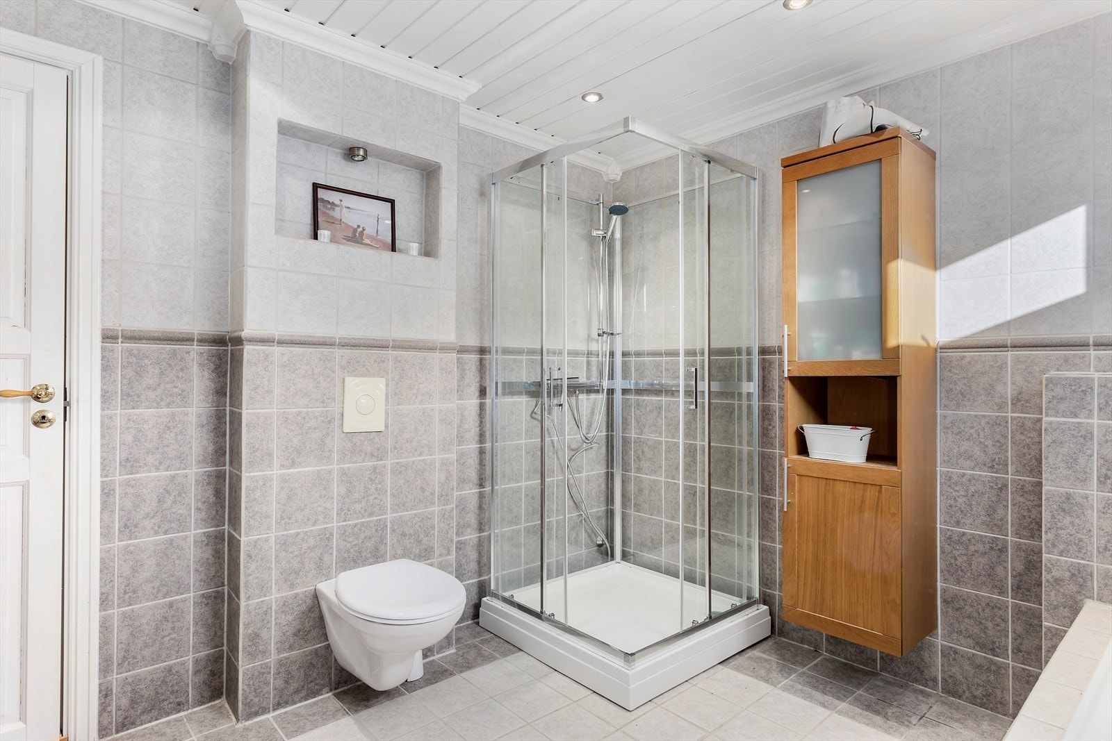 Badet er innredet med servantinnredning, høyskap, vegghengt toalett og dusjkabinett. Galleribilde