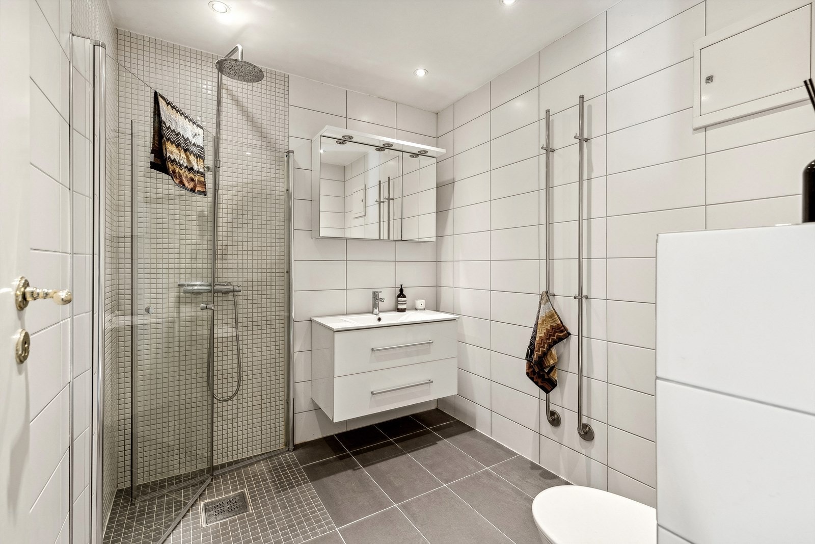 Lyst og delikat flislagt bad med integrert himlingbelysning Galleribilde