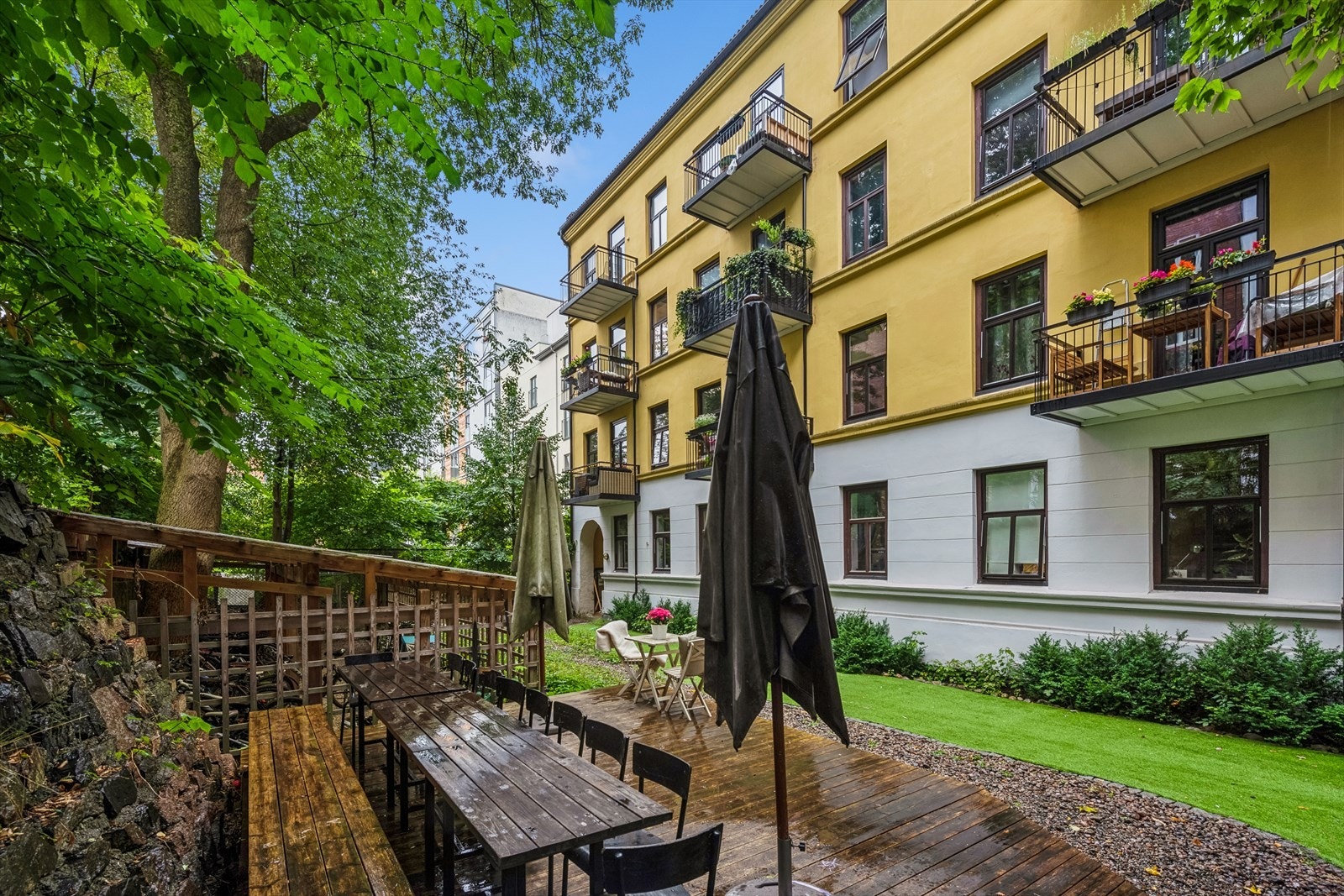 Koselig felles bakgård med gressplen, terrasser, trær, trampoline og sittegrupper Galleribilde