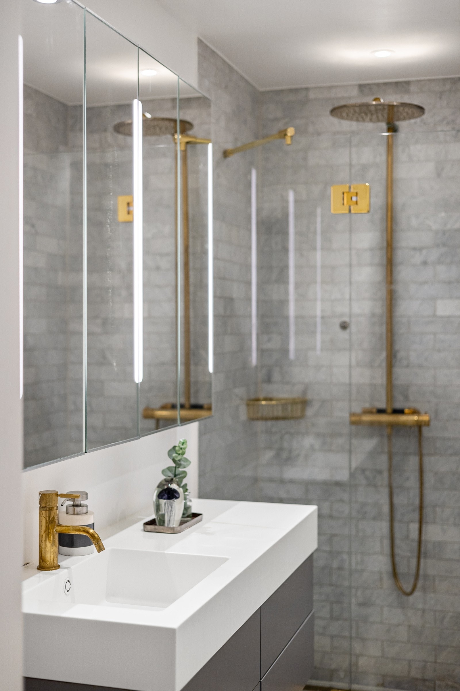 Moderne baderomsinnredning fra Corinor med skuffer og servant i Corian. Vegghengte speilskap med integrert belysning montert over innredningen. Galleribilde