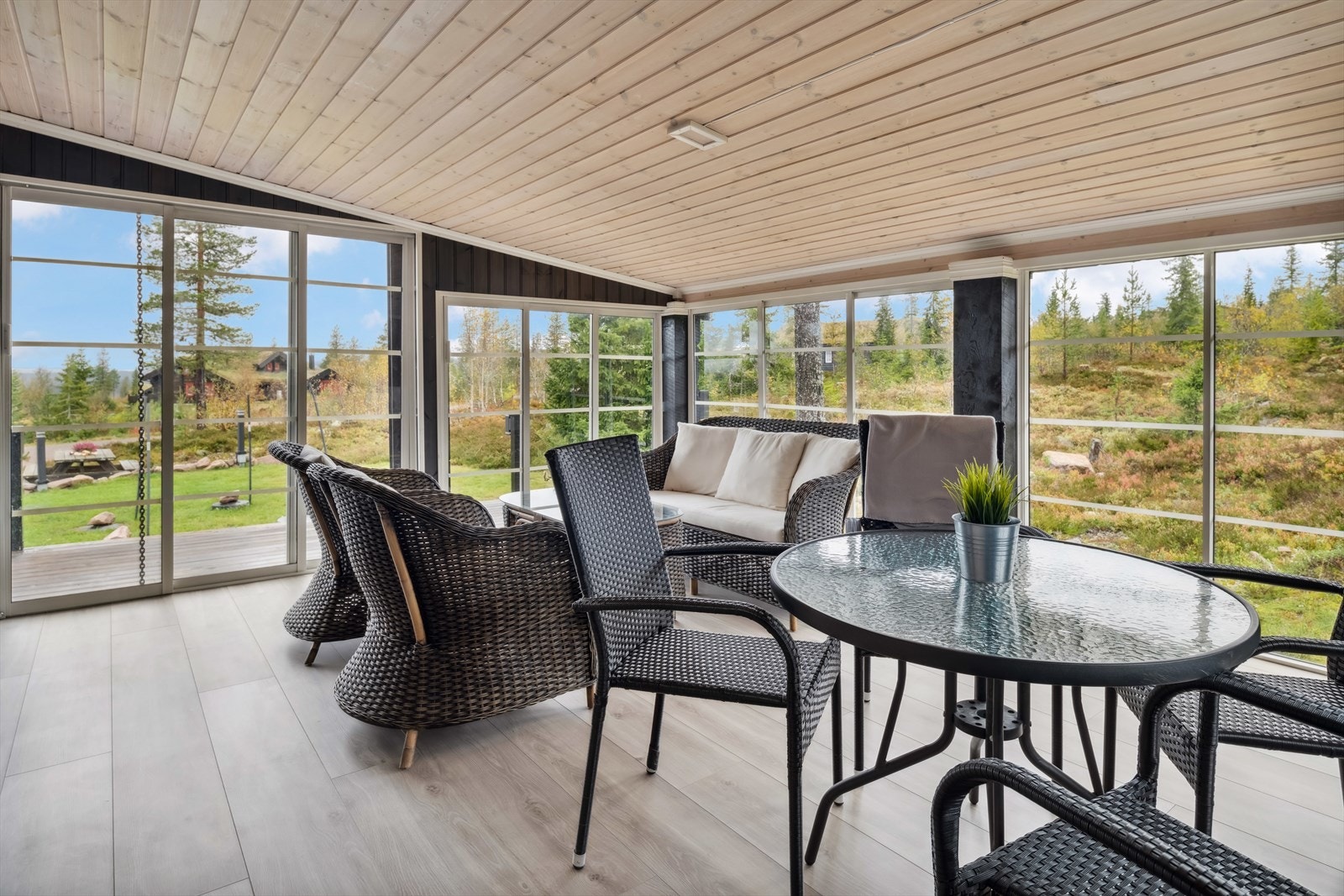 En storslått vinterhage med storevindusoverflater fra gulv til tak gir følelsen av å sitte ute med naturens omgivelser i all slags vær. Galleribilde