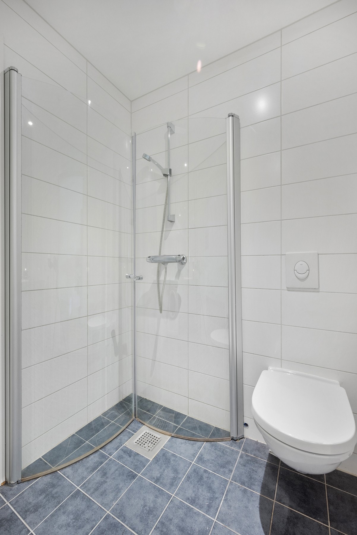 Badet har innredning med servant, veggmontert toalett, dusjvegger og opplegg for vaskemaskin. Galleribilde