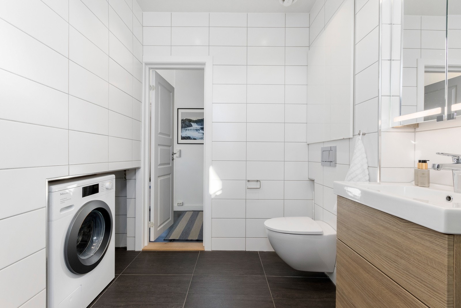 Badet har lekre fliser på gulv og vegger. Det er opplegg for vaskemaskin. Galleribilde