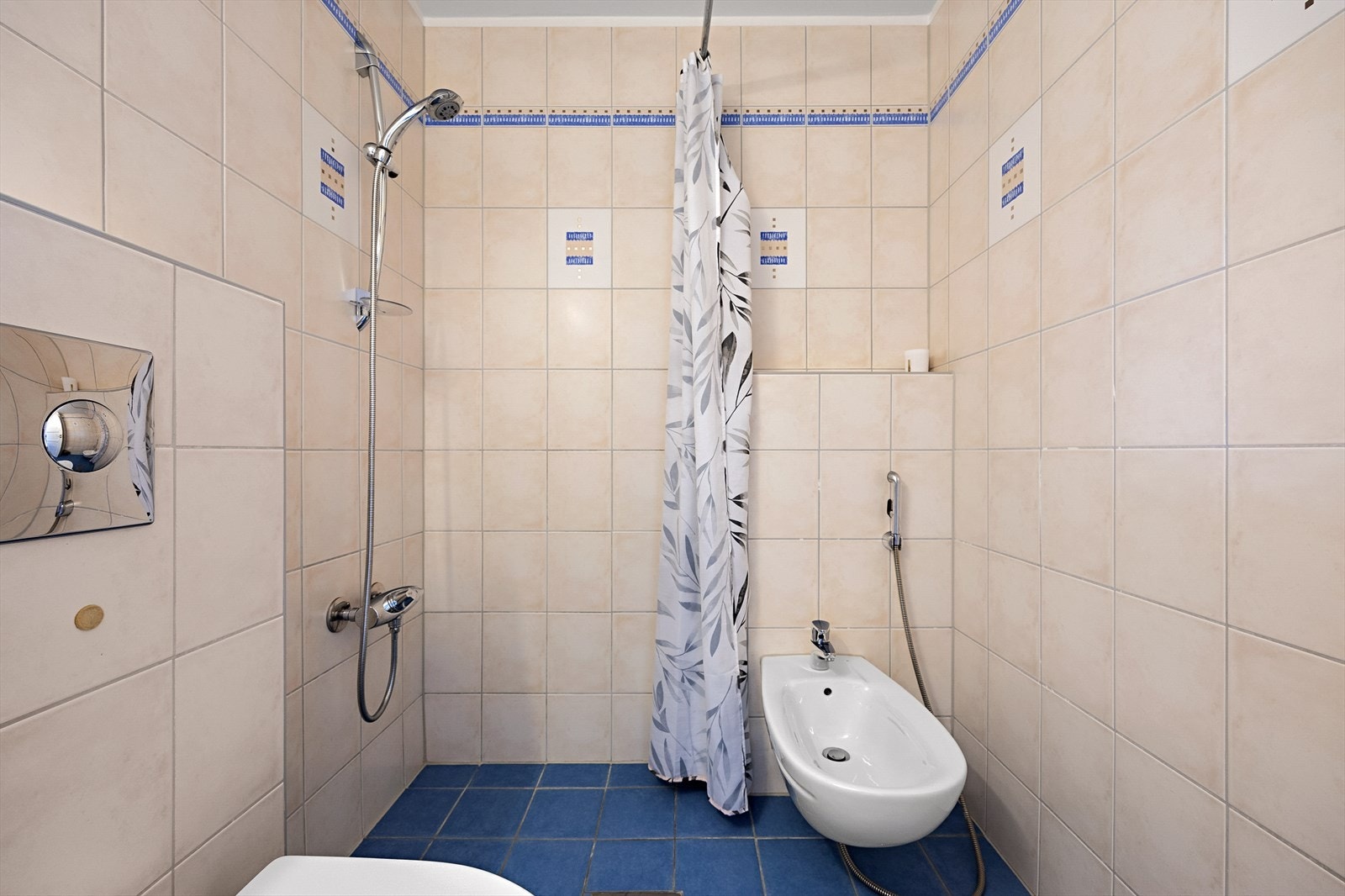Dette badet er utstyrt med dusjhjørne med forheng, vegghengt wc, bidé og servantinnredning med underskap Galleribilde
