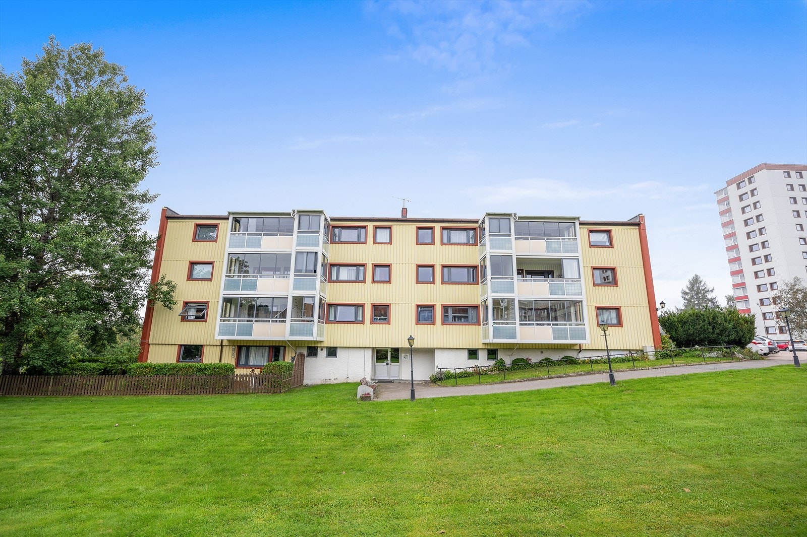 Bygning med innglasset balkong og velholdt uteområde. Galleribilde
