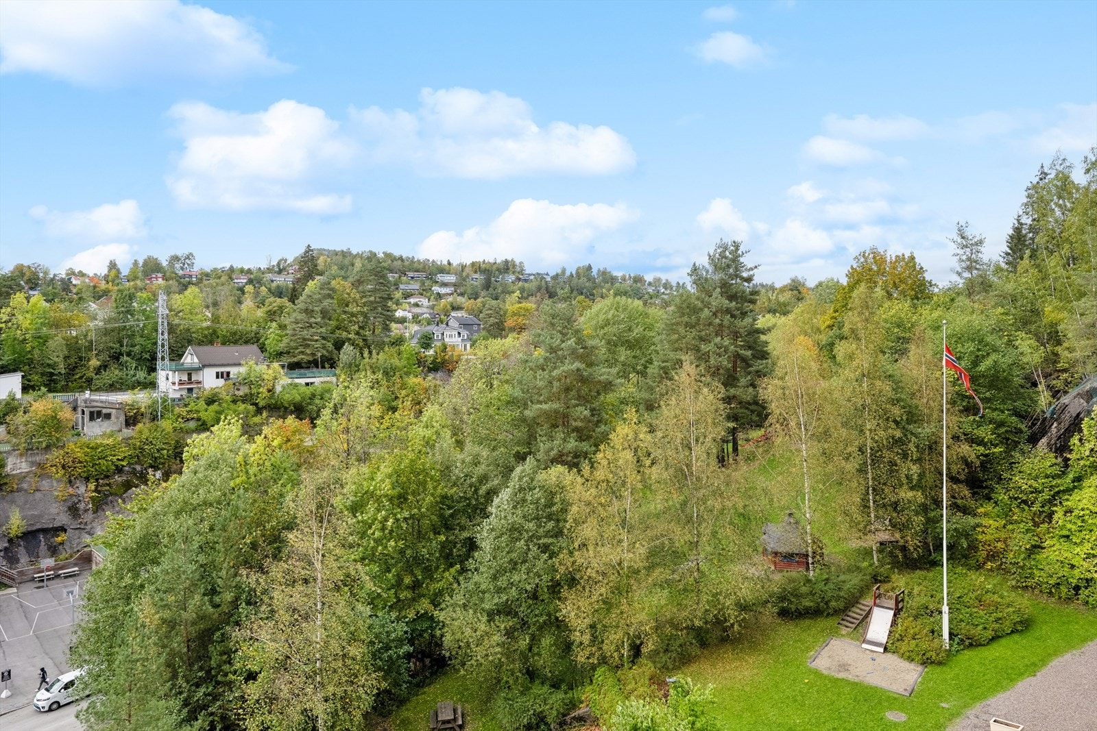 Like utenfor døren finner du et pent friområde med skog, sittebenker og lekeapparater Galleribilde