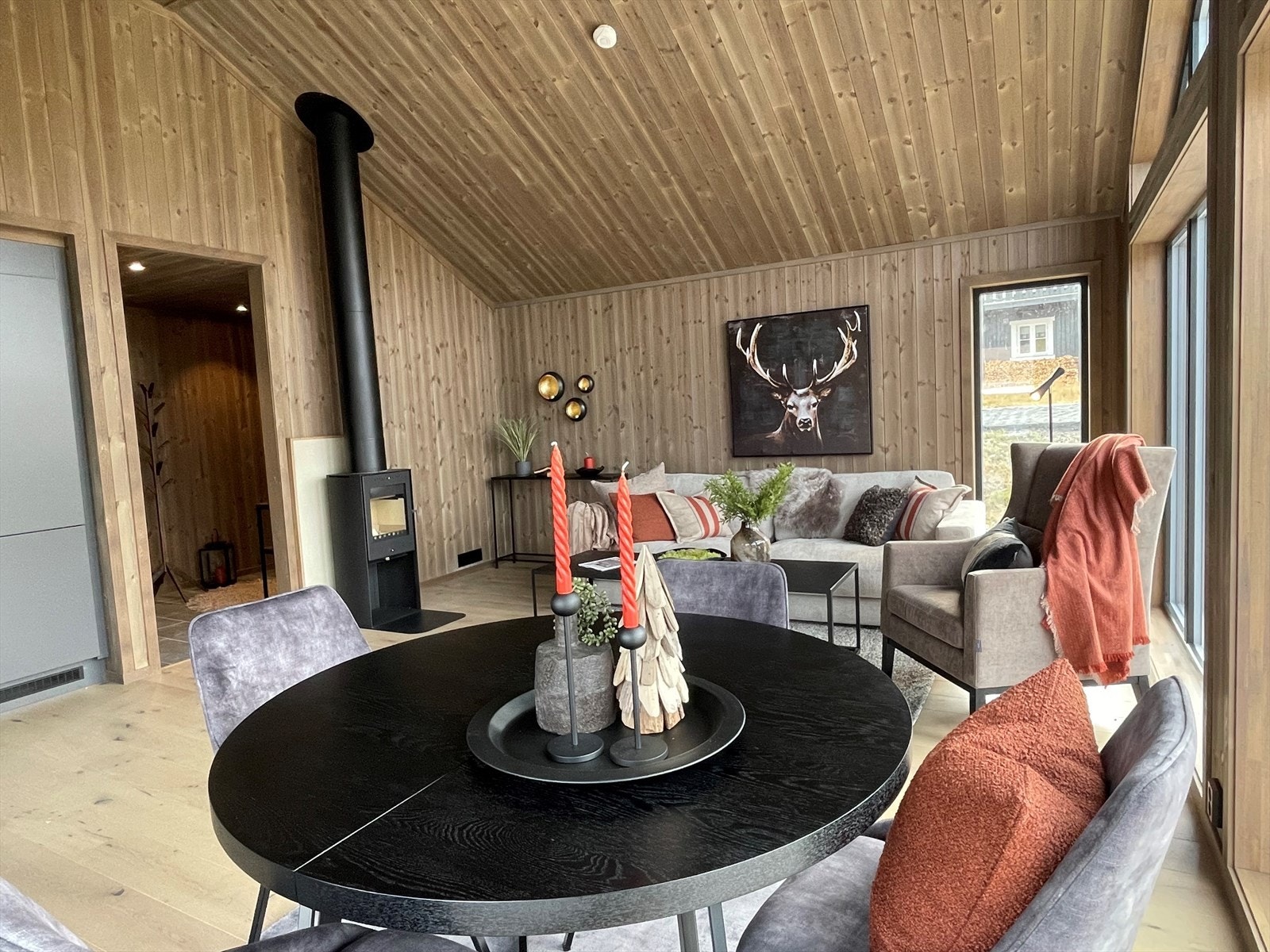 Det er fin plass til både sofa- og spisegruppe og en sort peisovn med stålpipe gir lun og god varme til rommet. Galleribilde