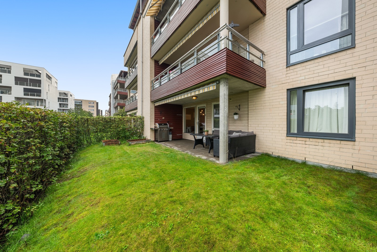 Utgang fra stue til vestvendt terrasse med en koselig hagedel. Galleribilde